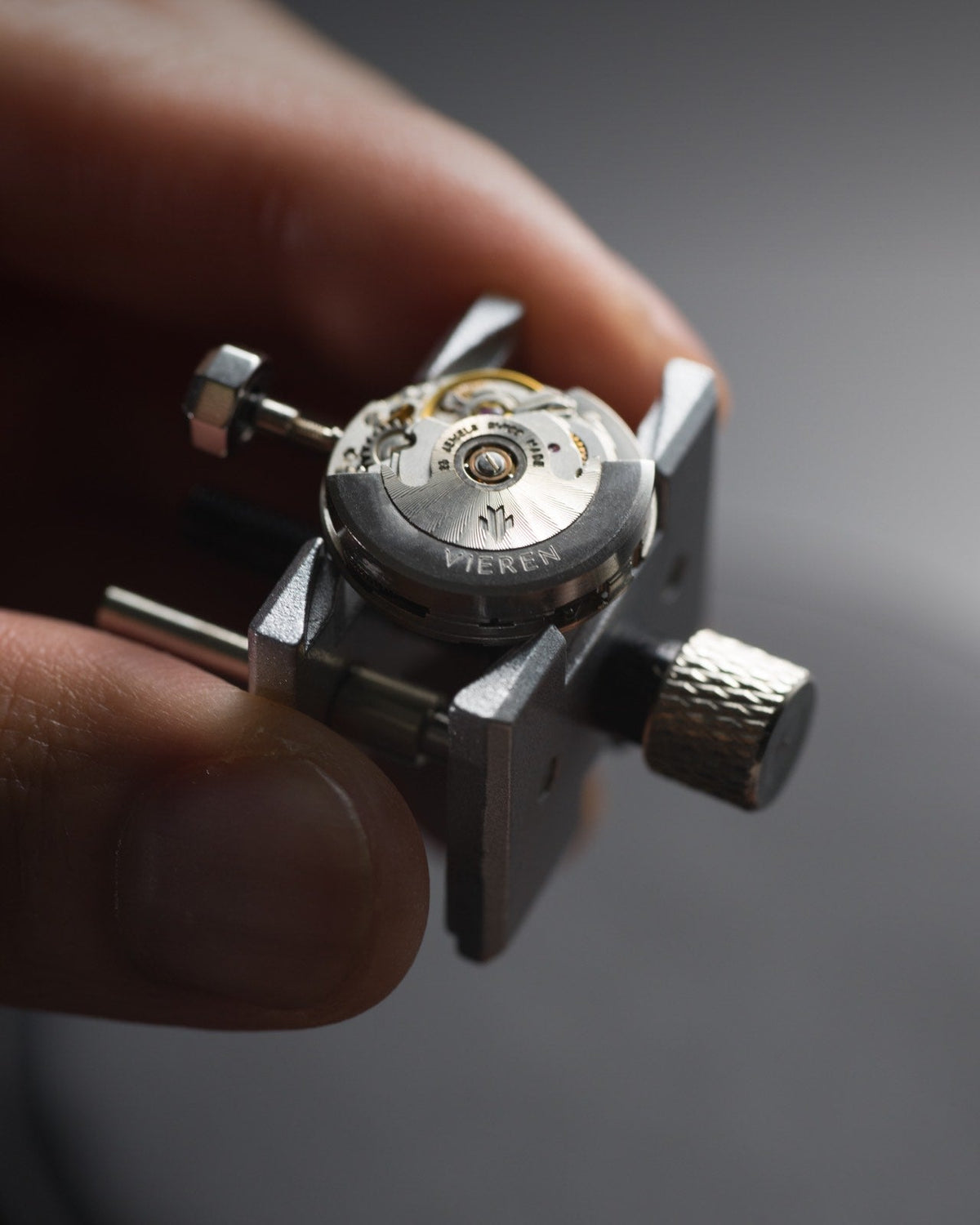 Close-up of hands holding ETA 2671 automatic watch movement in Swiss workshop