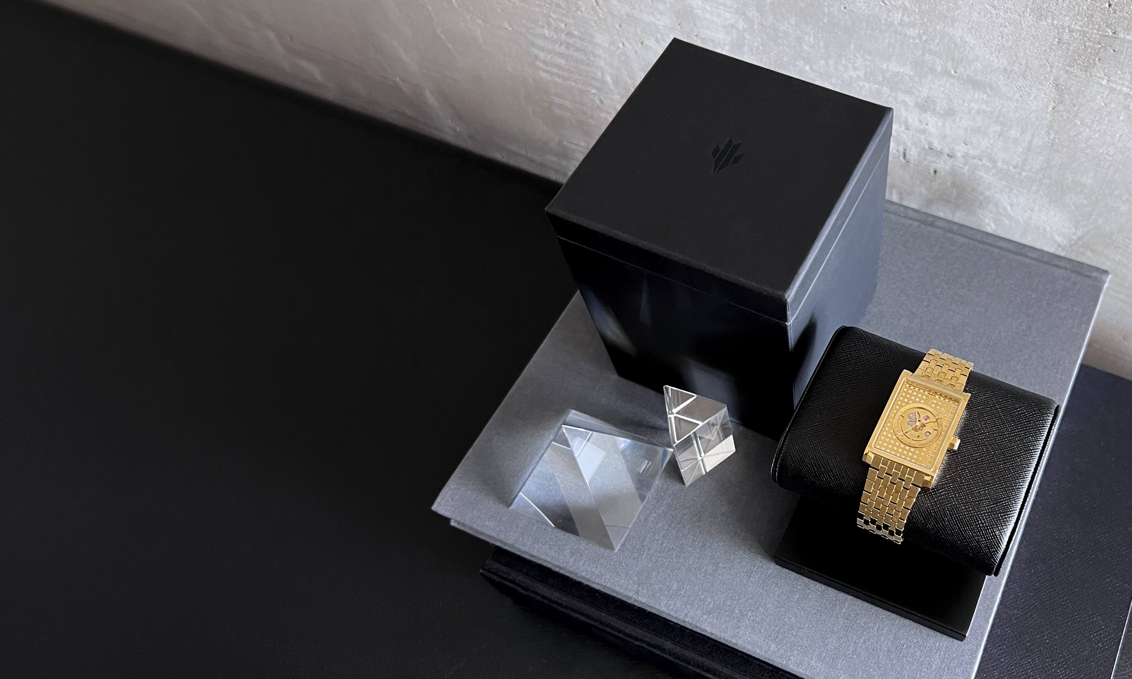 VIEREN Gold rectangular watch displayed on watch stand with signature box set and books in a lifestyle setting
