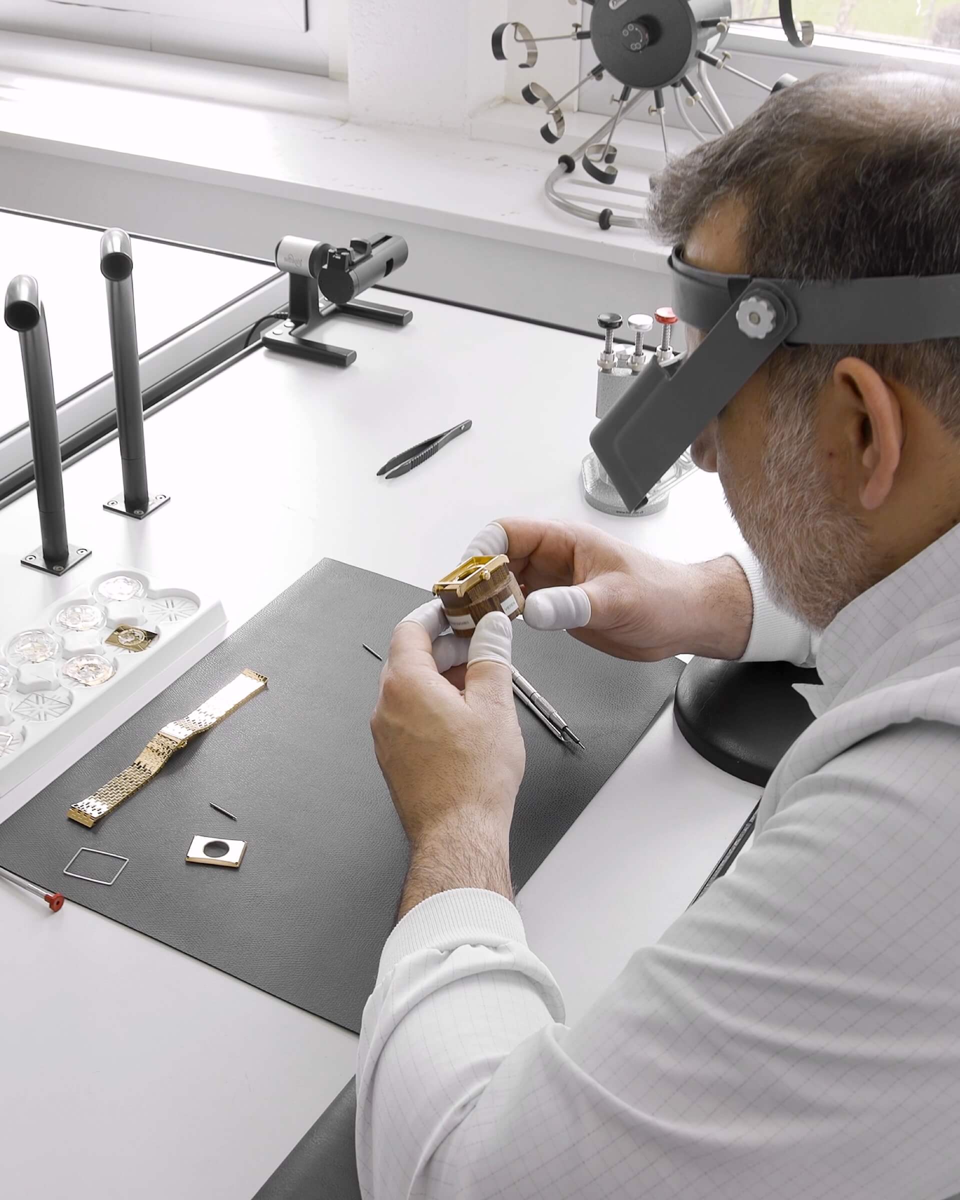 VIEREN Swiss watchmaker servicing gold rectangular watch parts with loupe and precision tools