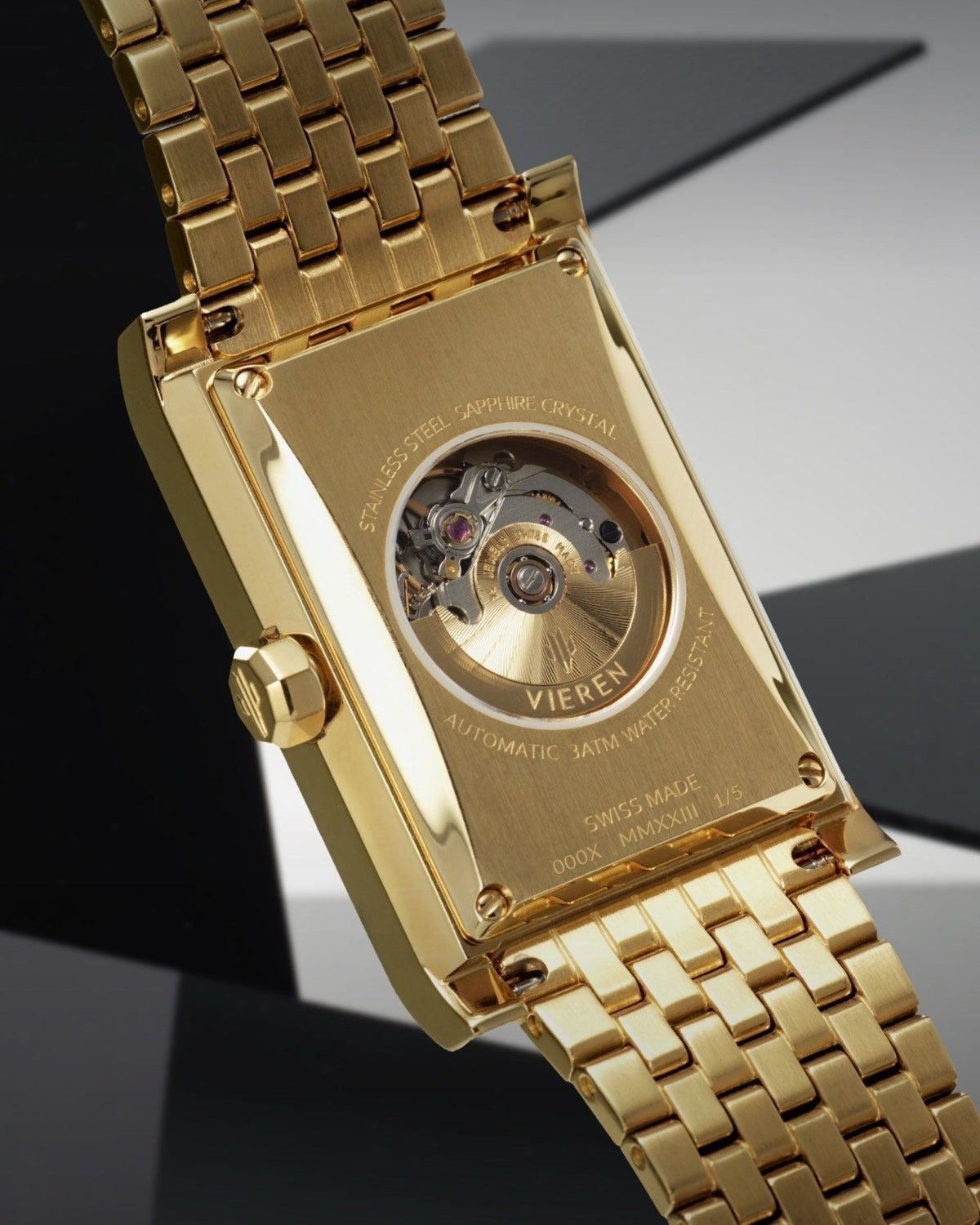 Gold rectangular watch caseback showing Swiss automatic movement with gold rotor