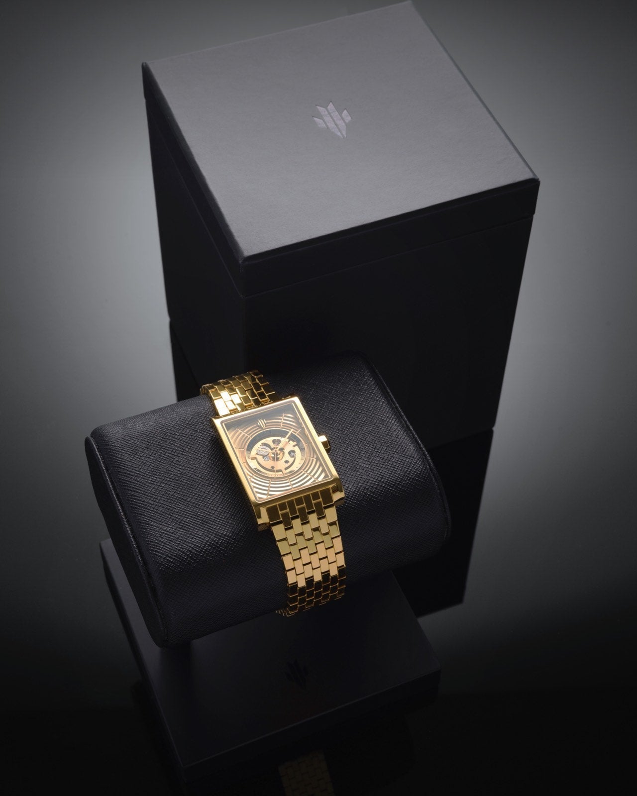 Swiss luxury gold rectangular watch displayed on a watch stand and box set