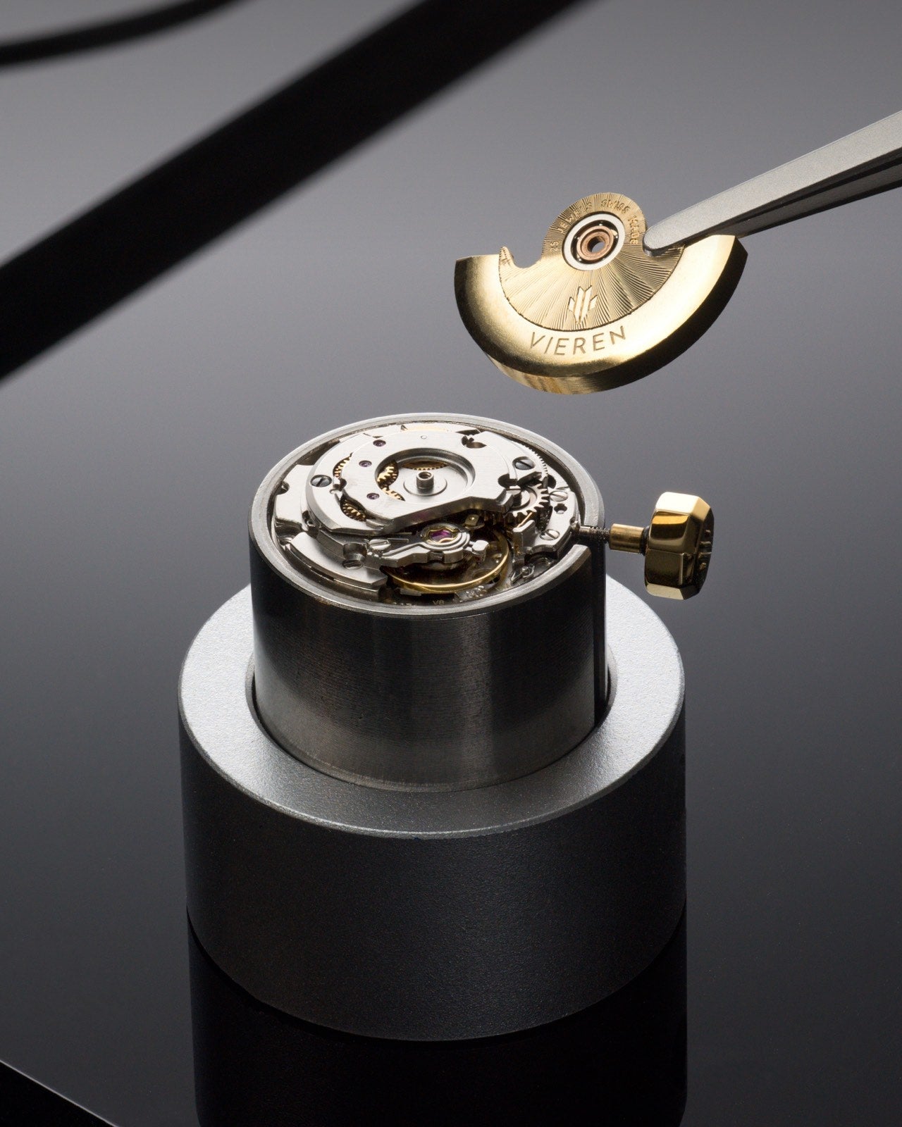 Luxury Swiss automatic watch movement with gold rotor being placed showing balance wheel and gears