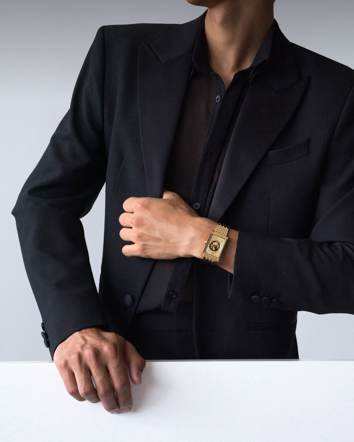 Swiss automatic luxury gold rectangular men’s watch styled with a black shirt and blazer