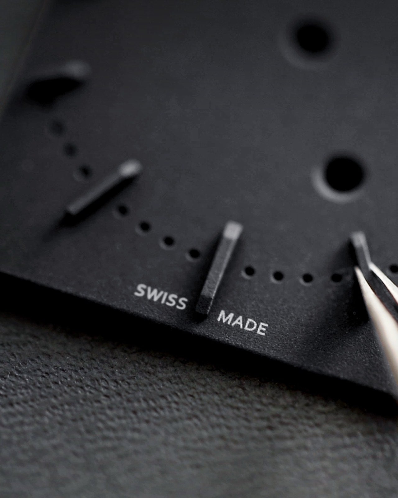 Closeup of Swiss Made label on black rectangular watch dial