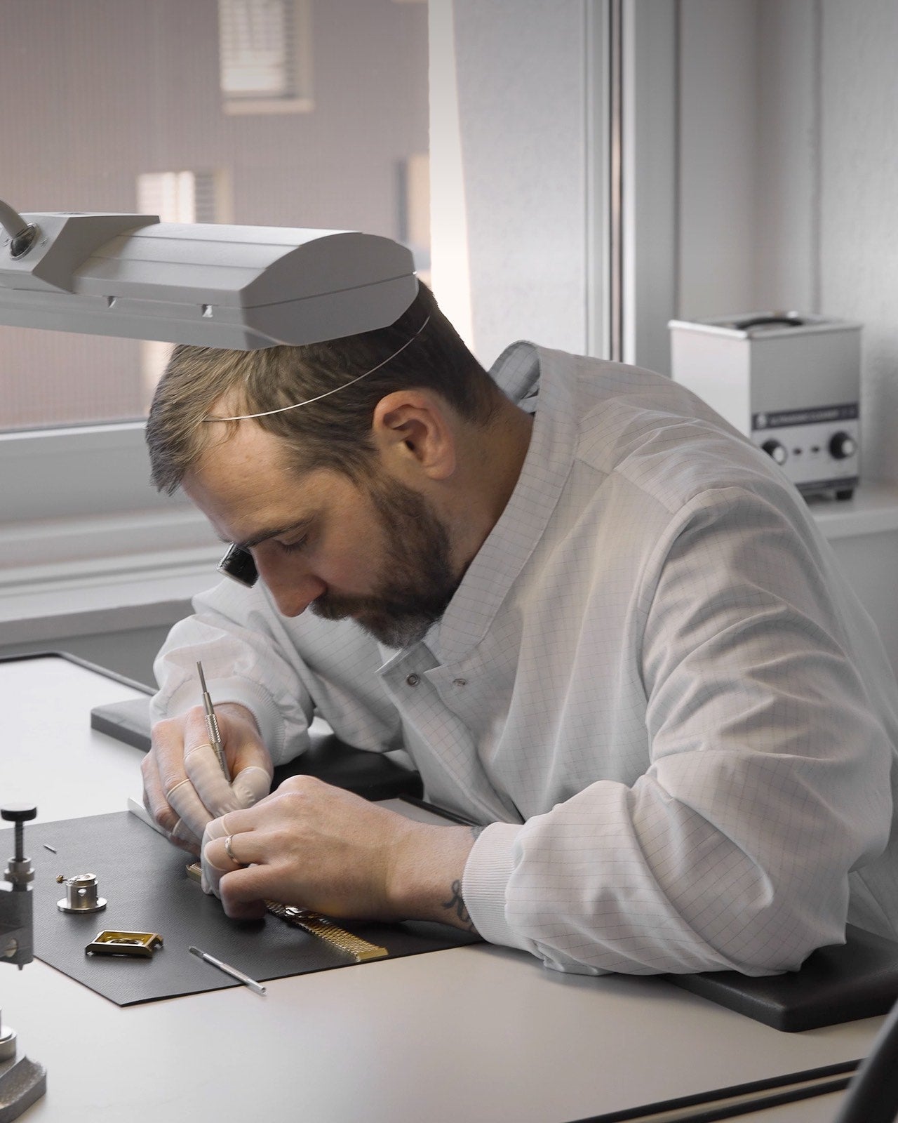 Swiss watchmaker servicing luxury automatic watch with loupe in studio 