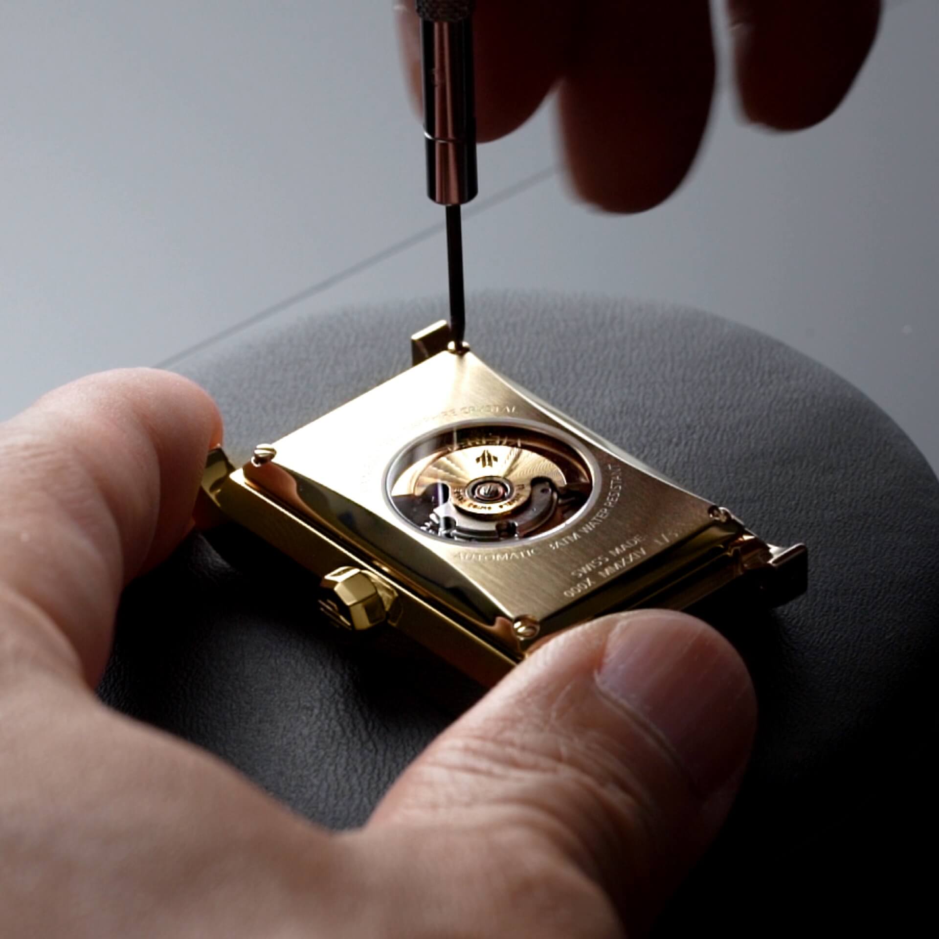 VIEREN Swiss watchmaker assembling gold rectangular watch caseback with automatic movement